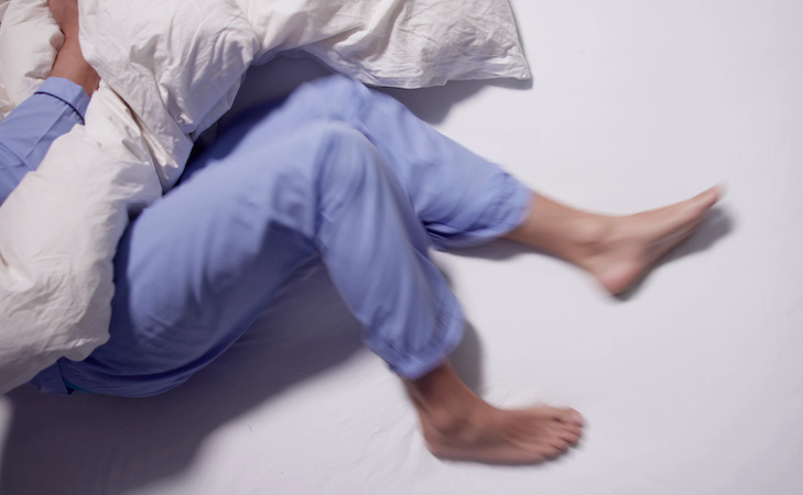 person with restless legs syndrome sleeping in bed