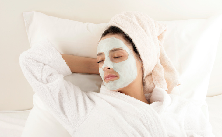 person with face mask on while lying down in bed