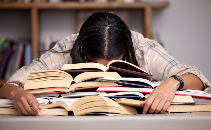 person sleeping on top of pile of books