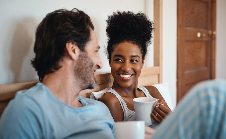 couple sitting in bed drinking coffee